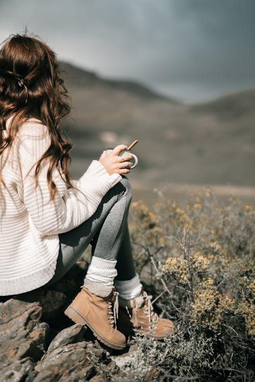 a woman wearing boots and sitting outdoors.