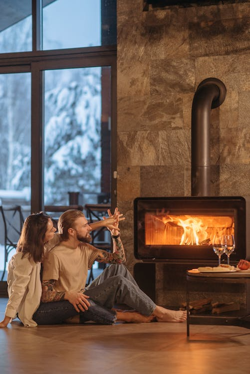 a couple sitting indoors by the fireplace.